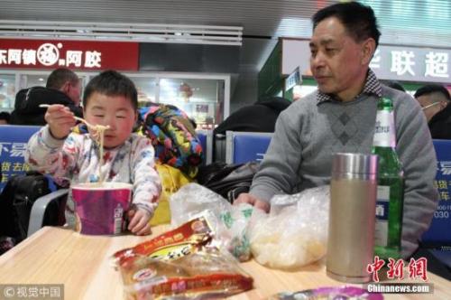 资料图:春运途中,有旅客喝着小酒就花生。图片来源:视觉中国 资料图:春运途中,有旅客喝着小酒就花生。图片来源:视觉中国